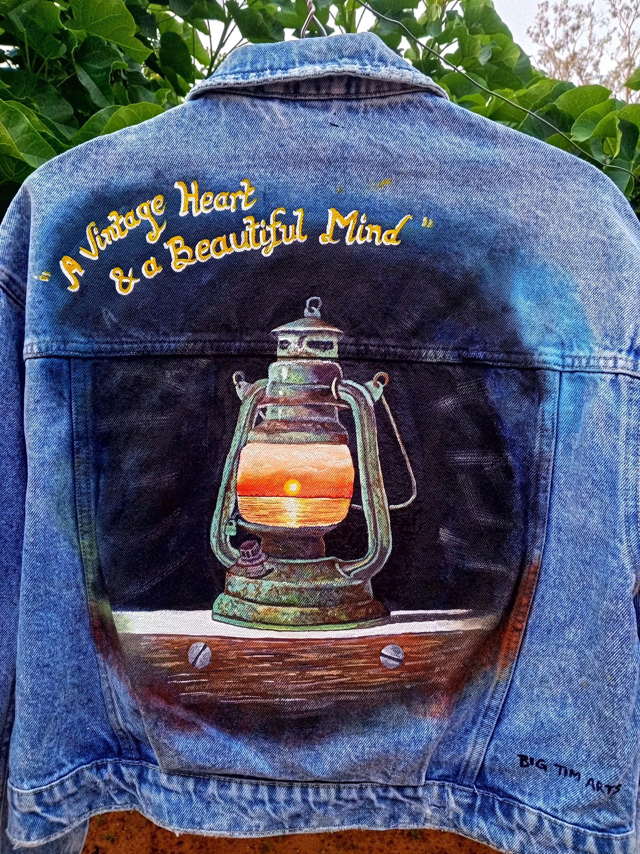 Lantern painted on the back of a denim jacket with gold lettering.