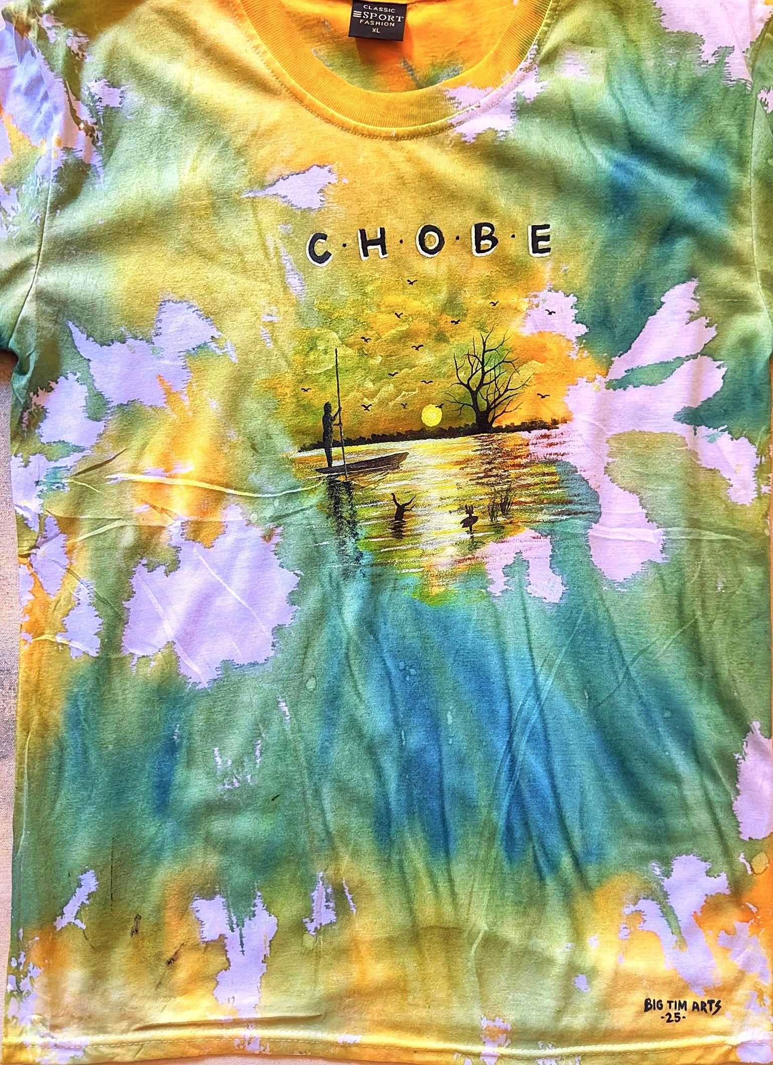 Green and yellow tie-dyed shirt with a painted river sunset and lettering.