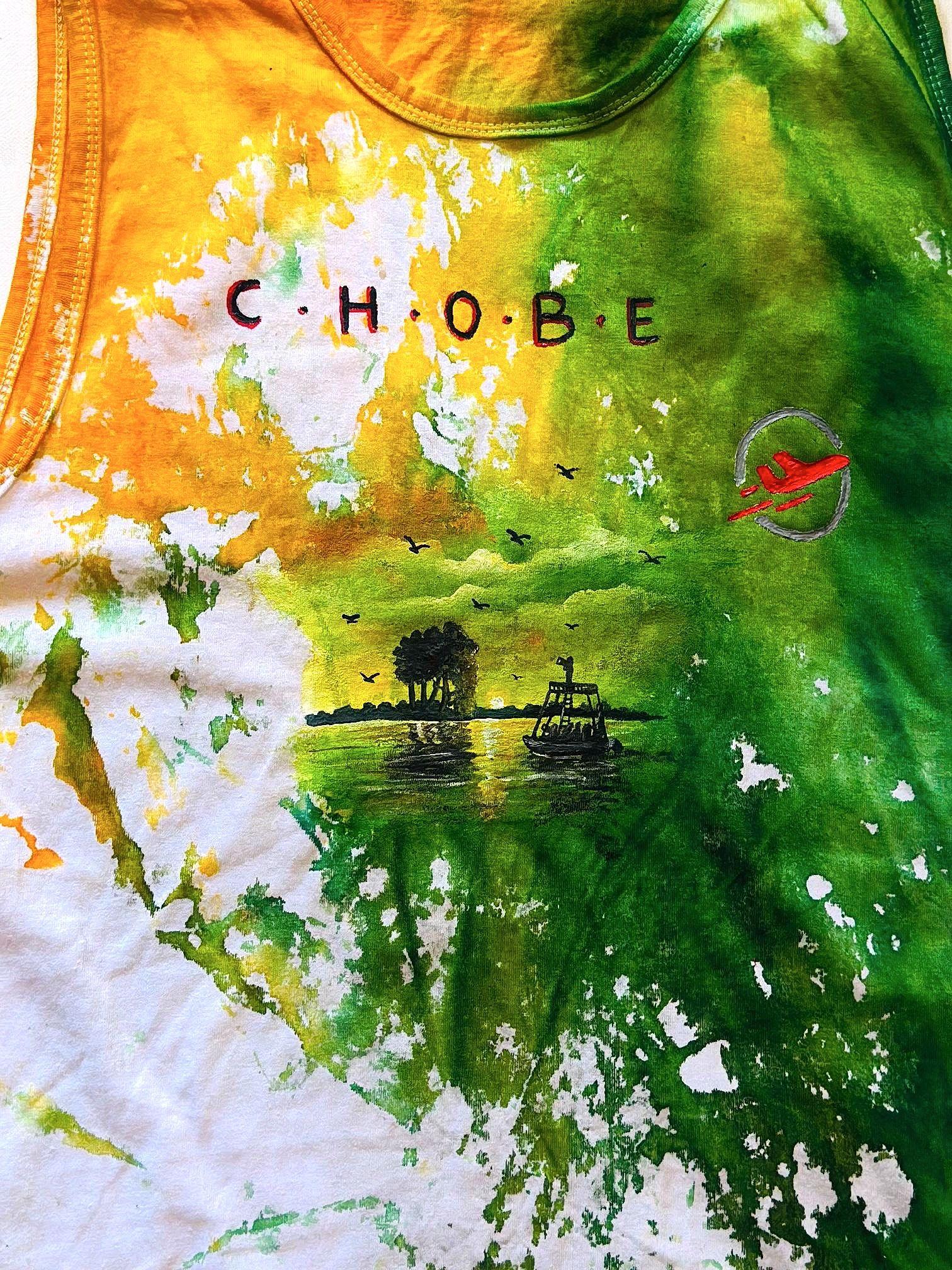 Green, yellow and white painted shirt with a river scene and lettering.