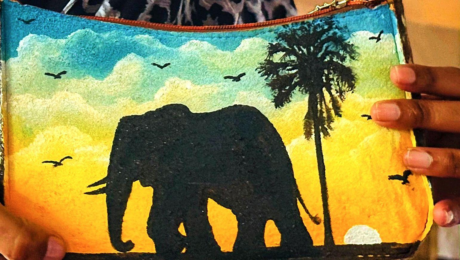 Elephant and palm silhouettes against a yellow and blue sky on a bag.