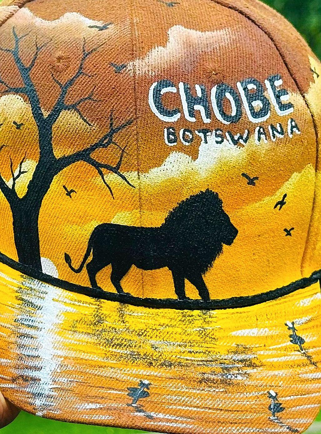 Lion silhouette and bare tree above golden water on a cap.