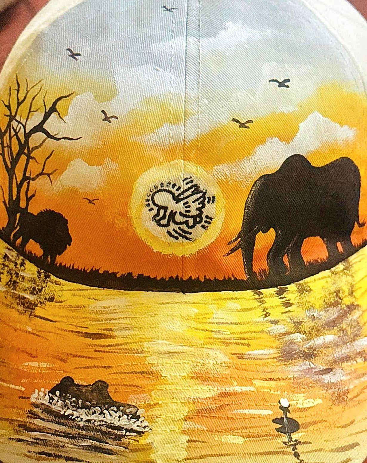 Elephants, a bare tree, and birds above golden water on a cap.