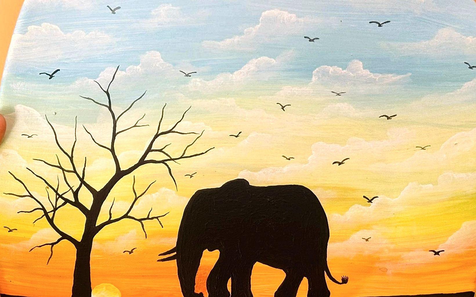 Elephant and bare tree silhouettes beneath a blue and golden sky.