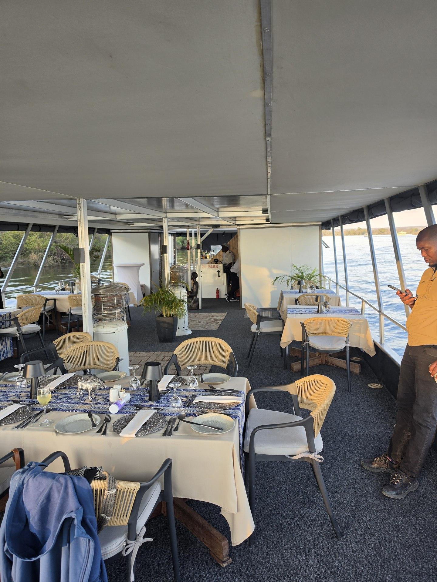 Tables are laid with glasses and plates inside the river boat.