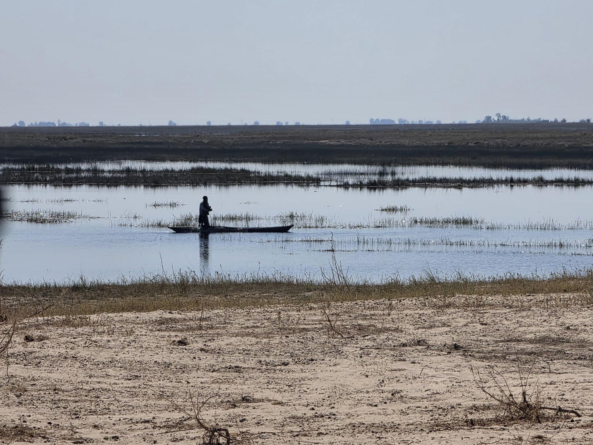 A silhouetted person is visible in a narrow canoe on calm water.