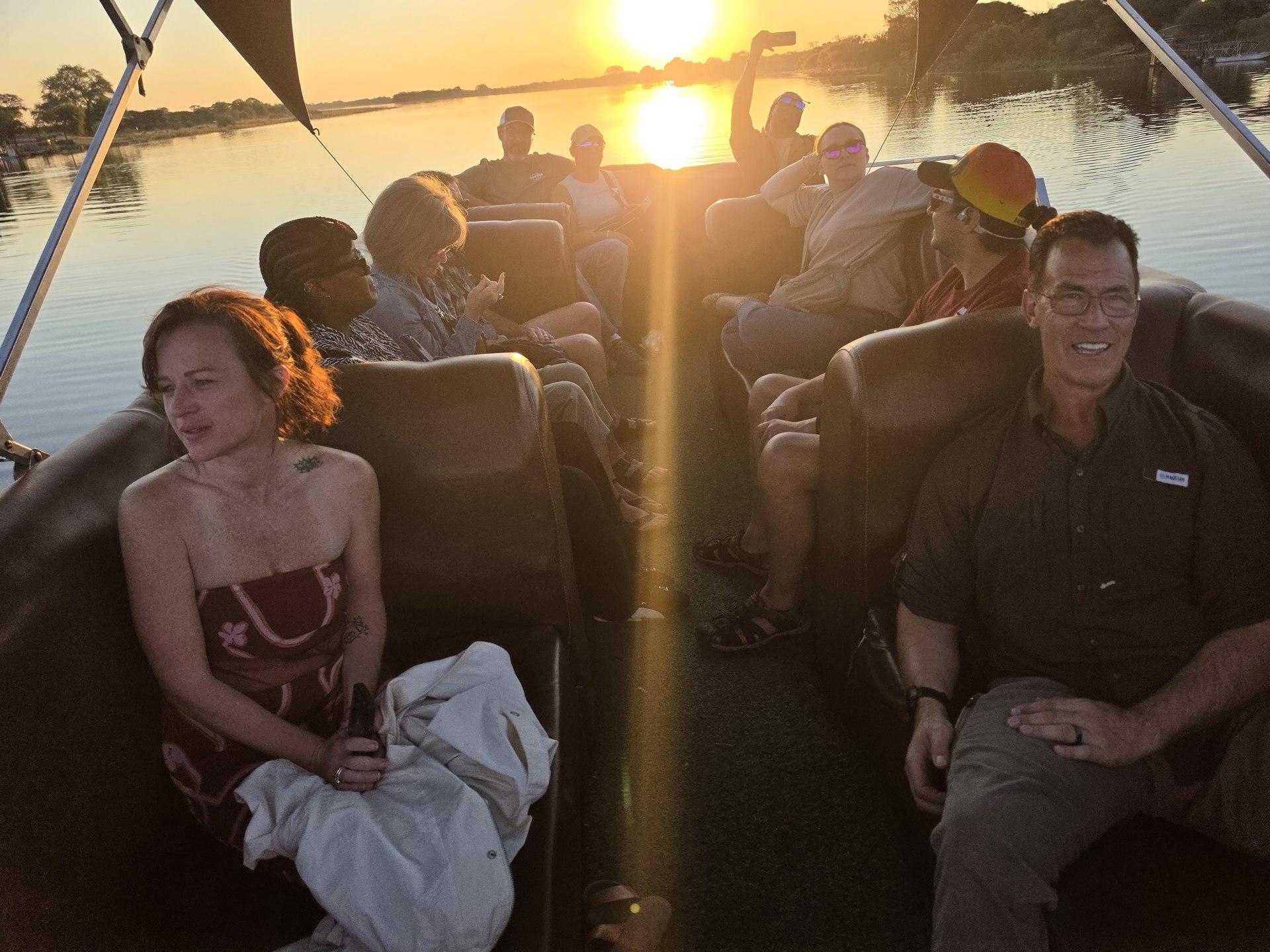 Guests relaxing on a boat at sunset; strong warm light and spontaneous gestures.