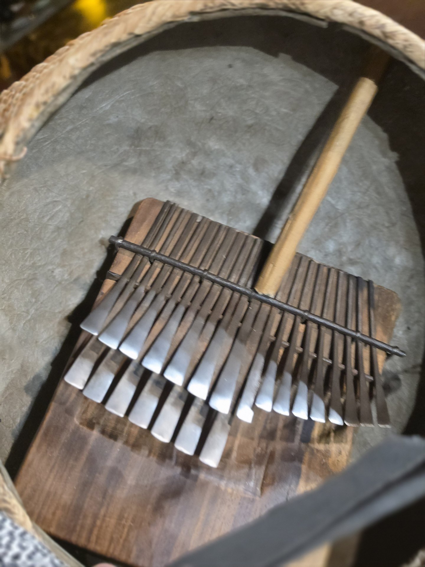 Close view of a wooden thumb piano resting against a drum.