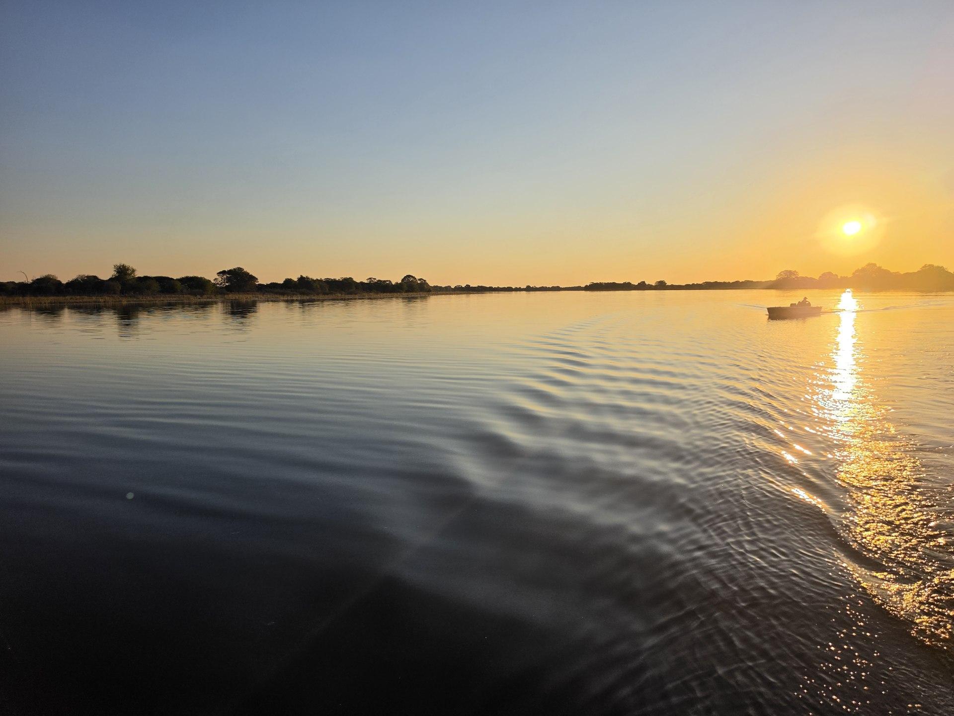 Warm river sunset with a small boat and rippling reflections.